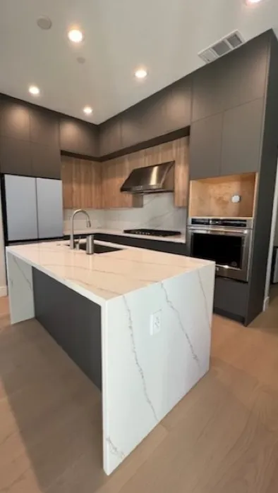 Custom dark flat-panel kitchen with quartz waterfall island