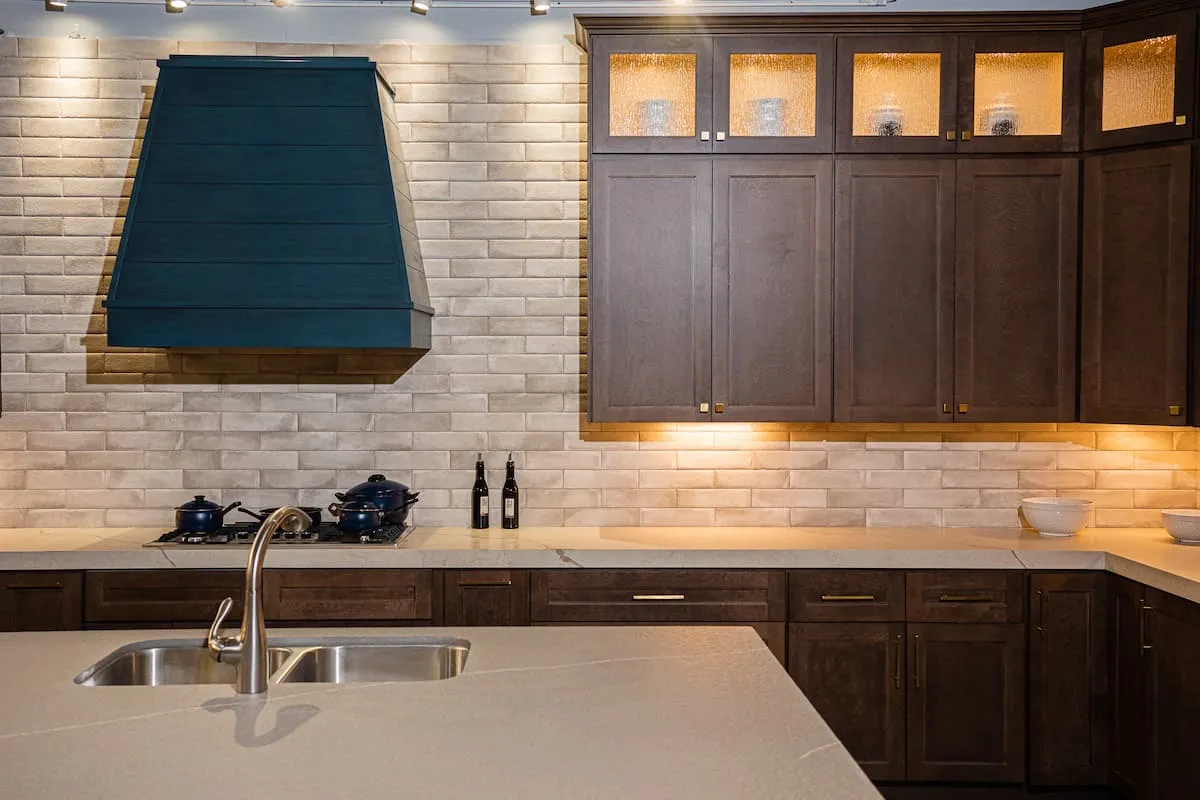 Espresso cabinets with glass uppers and a teal range hood