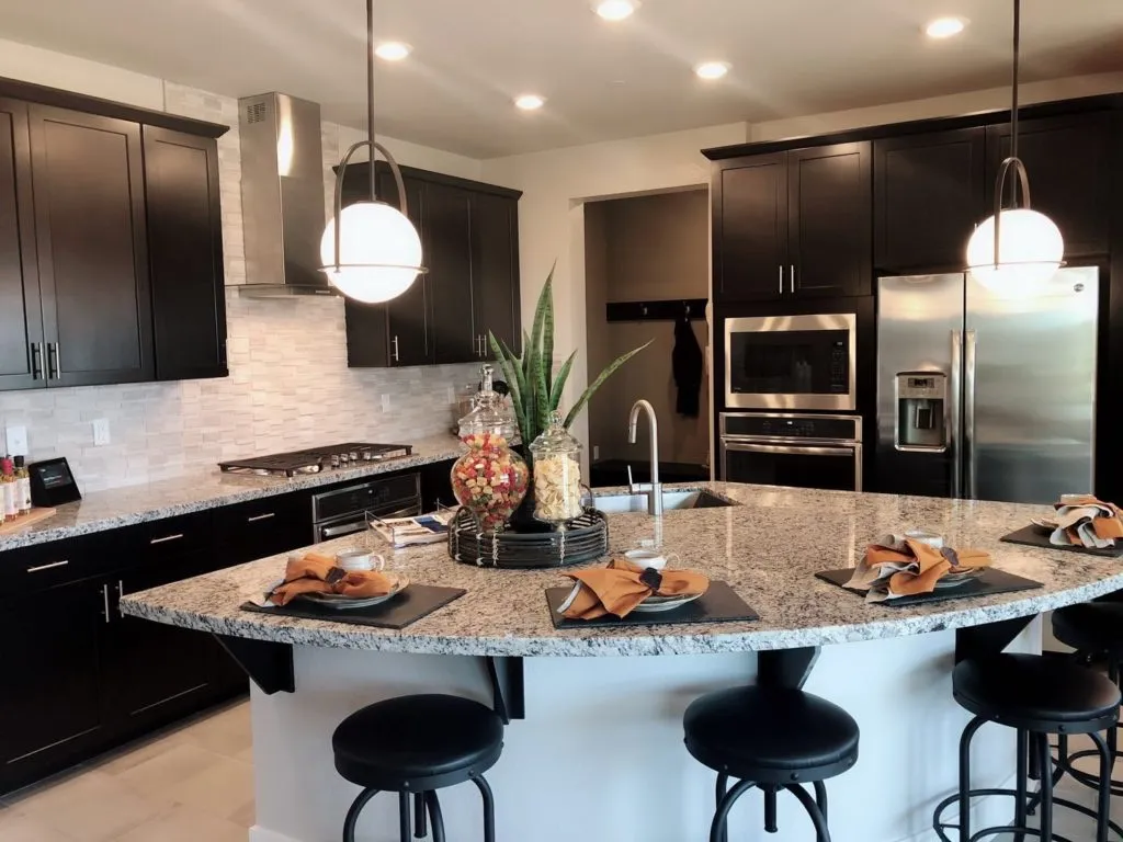 Espresso cabinets with a curved granite island and globe pendants