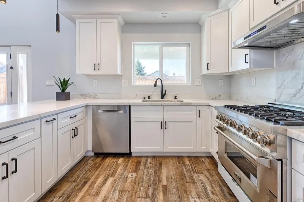 White shaker kitchen with marble-look backsplash and stainless range