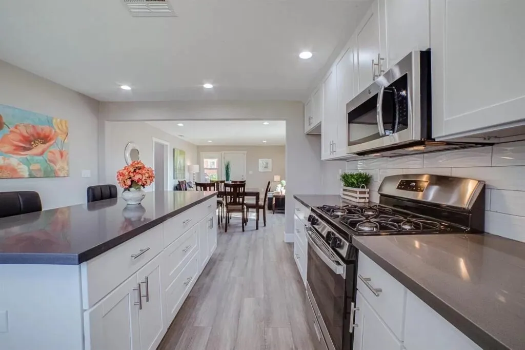 White kitchen with grey countertops opening to a dining area